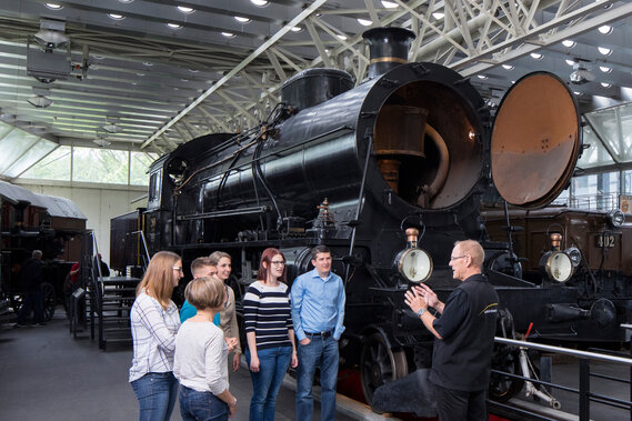 Ein Guide erklärt einer Gruppe die Eisenbahn Elefant im Verkehrshaus.