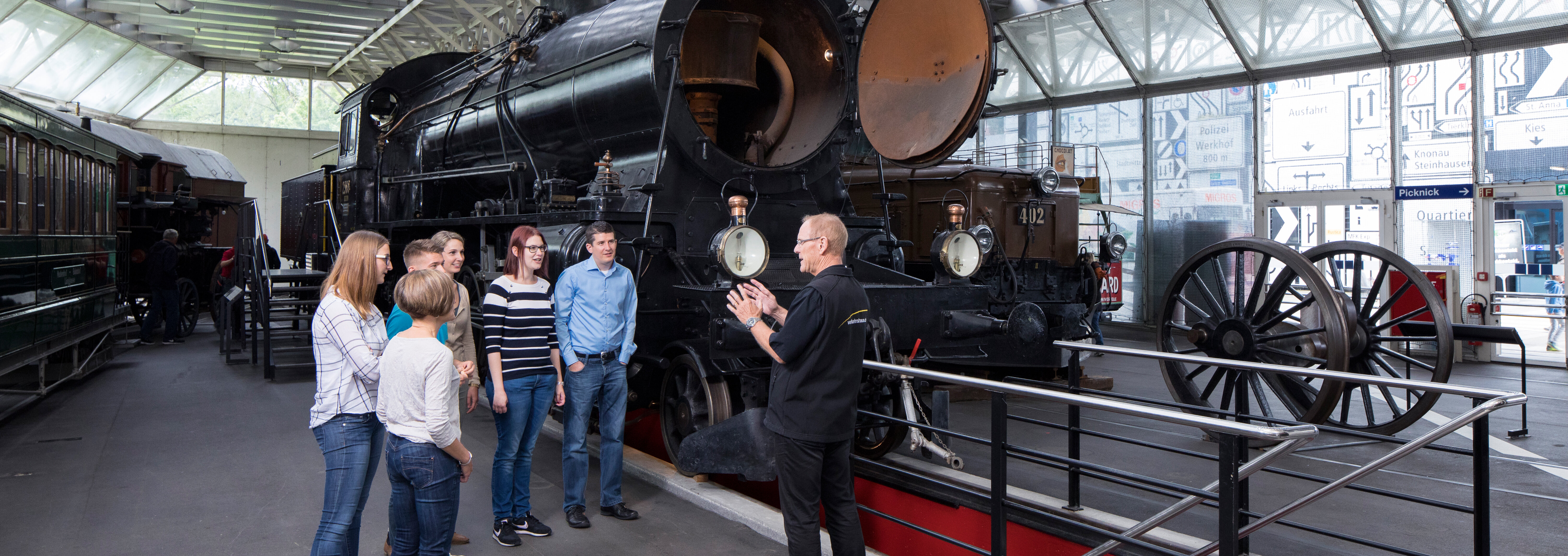 Ein Guide erklärt einer Gruppe die Eisenbahn Elefant im Verkehrshaus.