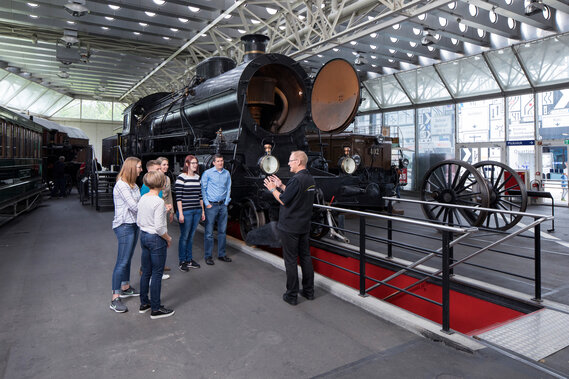 Ein Guide erklärt einer Gruppe die Eisenbahn Elefant im Verkehrshaus.