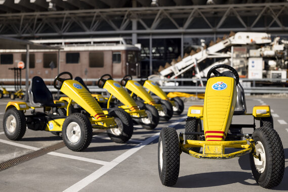 Gelbe Gokarts stehen in einer Reihe draussen in der Verkehrshausarena.