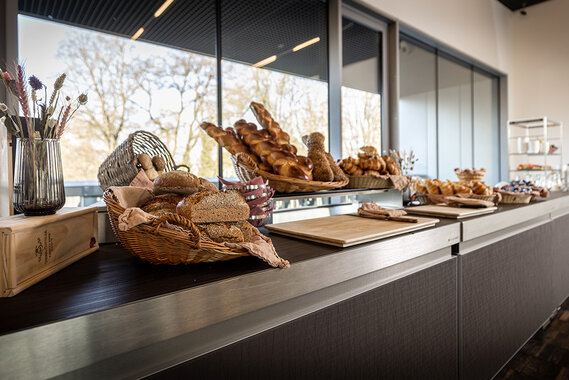 Eine schön gestaltete Frühstückstheke mit verschiedenen Brotsorten in Körben.