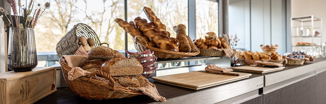 Eine schön gestaltete Frühstückstheke mit verschiedenen Brotsorten in Körben.