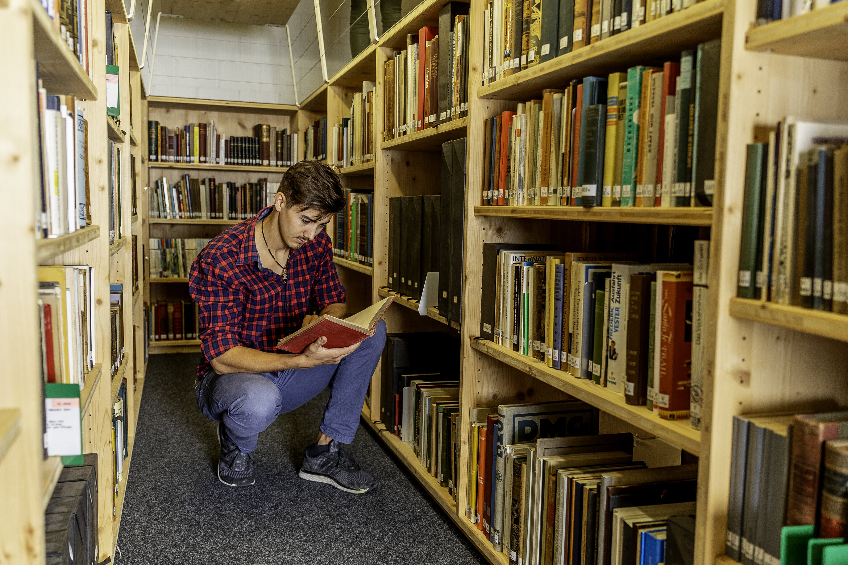 Eine Person liest ein Buch zwischen Bücherregalen in der Bibliothek des Dokuzentrums im Verkehrshaus.