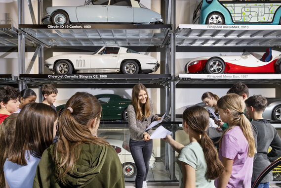 Eine Lehrerin verteilt Arbeitsblätter einer Schulklasse im Verkehrshaus.