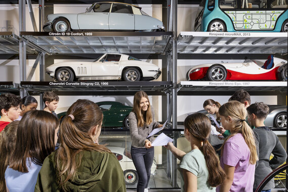 Eine Lehrerin verteilt Arbeitsblätter einer Schulklasse im Verkehrshaus.