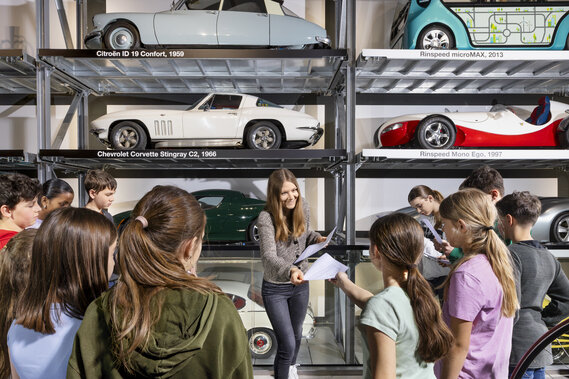 Eine Lehrerin verteilt Arbeitsblätter einer Schulklasse im Verkehrshaus.