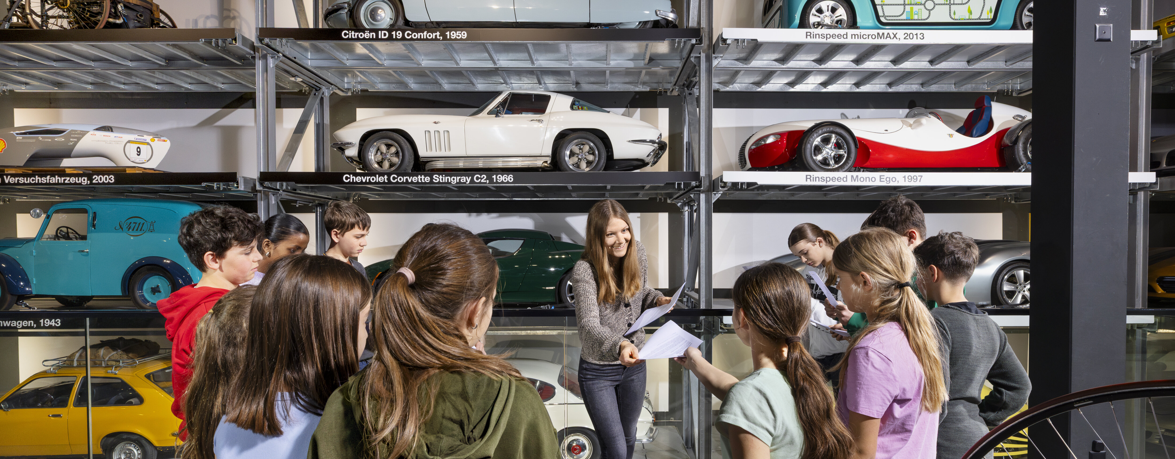 Eine Lehrerin verteilt Arbeitsblätter einer Schulklasse im Verkehrshaus.