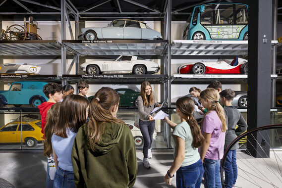 Eine Lehrerin verteilt Arbeitsblätter einer Schulklasse im Verkehrshaus.