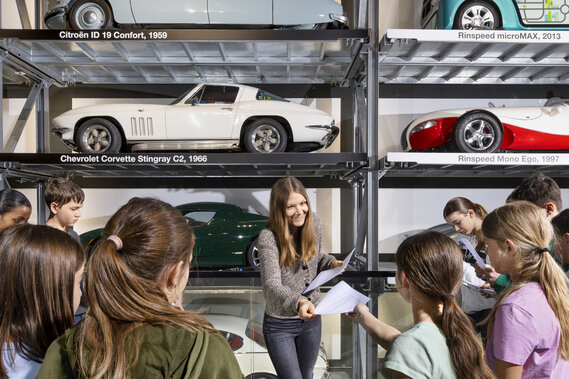 Eine Lehrerin verteilt Arbeitsblätter einer Schulklasse im Verkehrshaus.