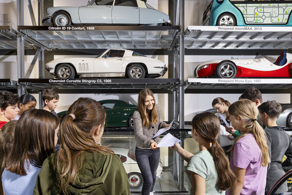 Eine Lehrerin verteilt Arbeitsblätter einer Schulklasse im Verkehrshaus.
