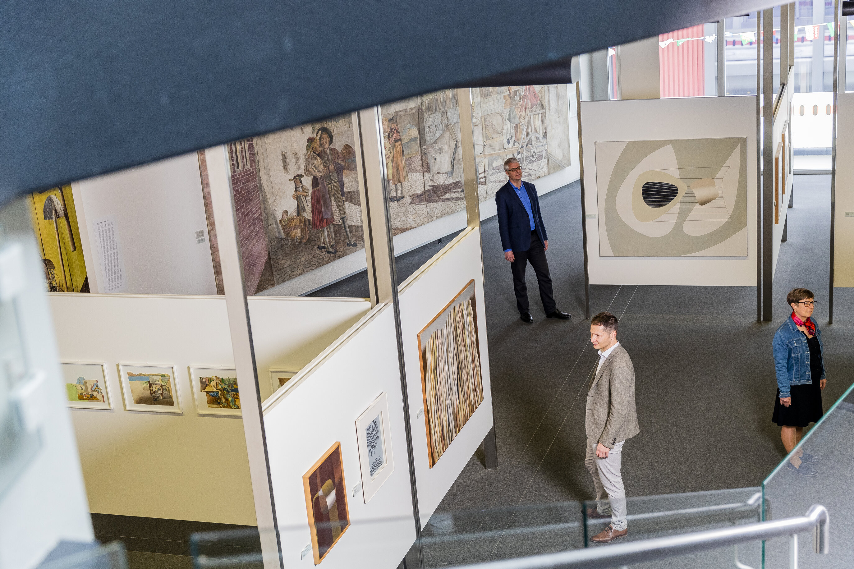 Drei Besucher laufen im Museum herum und bestaunen die verschiedenen Werke der Exhibition.