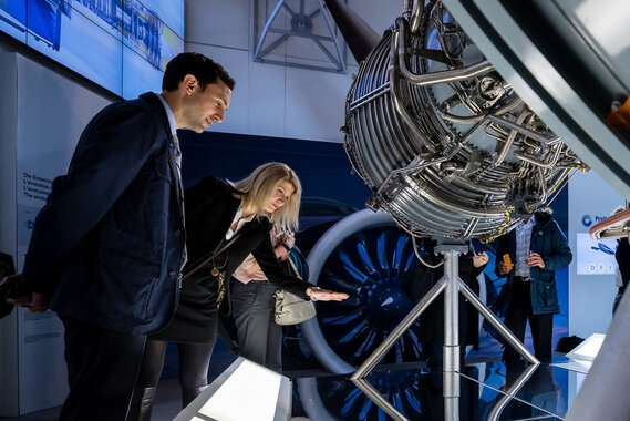 Eine Frau und ein Mann starren auf ein Flugzeugmotor.