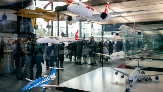 Eine Ausstellung von Miniatur-Flugzeugmodellen, unter anderem der Fluggesellschaften Swiss und Helvetic, in einem modernen Ambiente und unter lebhaftem Publikum.