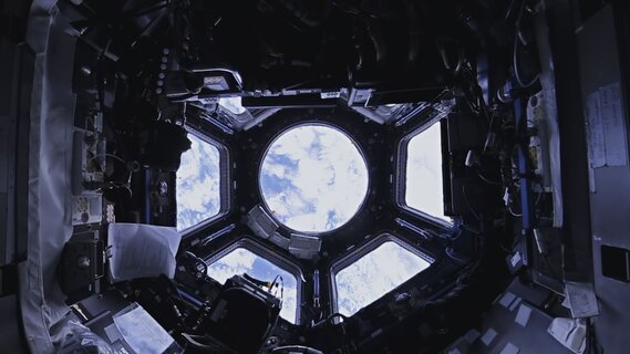 Durch das Fenster der Raumstation ISS blickt man auf die Erde.
