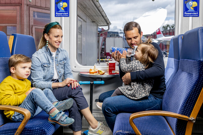 Eine vierköpfige Familie isst in einem Bahnwagen Picknick.