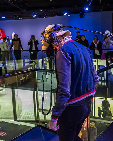 Eine Person mit VR-Headset steht auf einer Glasplattform, die das Red Bull-Logo zeigt.
