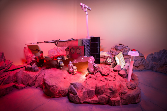 Ein Roboter-Rover auf einem felsigen, beleuchteten Gelände mit Sci-Fi-Elementen und Informationsanzeigen inmitten einer farbenfrohen, stimmungsvollen Kulisse.
