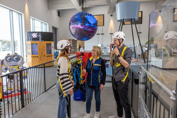 Eine Verkehrshausmitarbeiterin weist zwei Besucher für die Stromreise im Verkehrshaus ein.