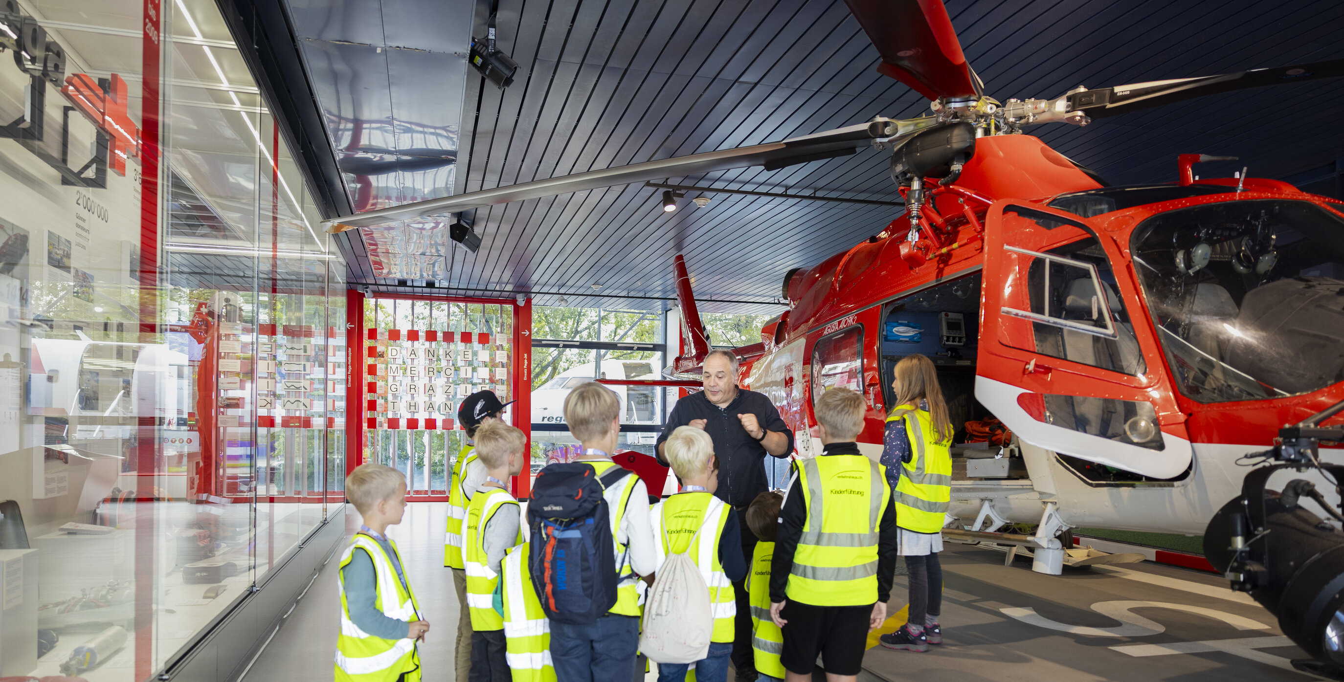 Fünf Kinder mit Leuchtwesten und eine Begleitperson mit Leuchtweste, sie stehen im Verkehrsgarten im Verkehrshaus.