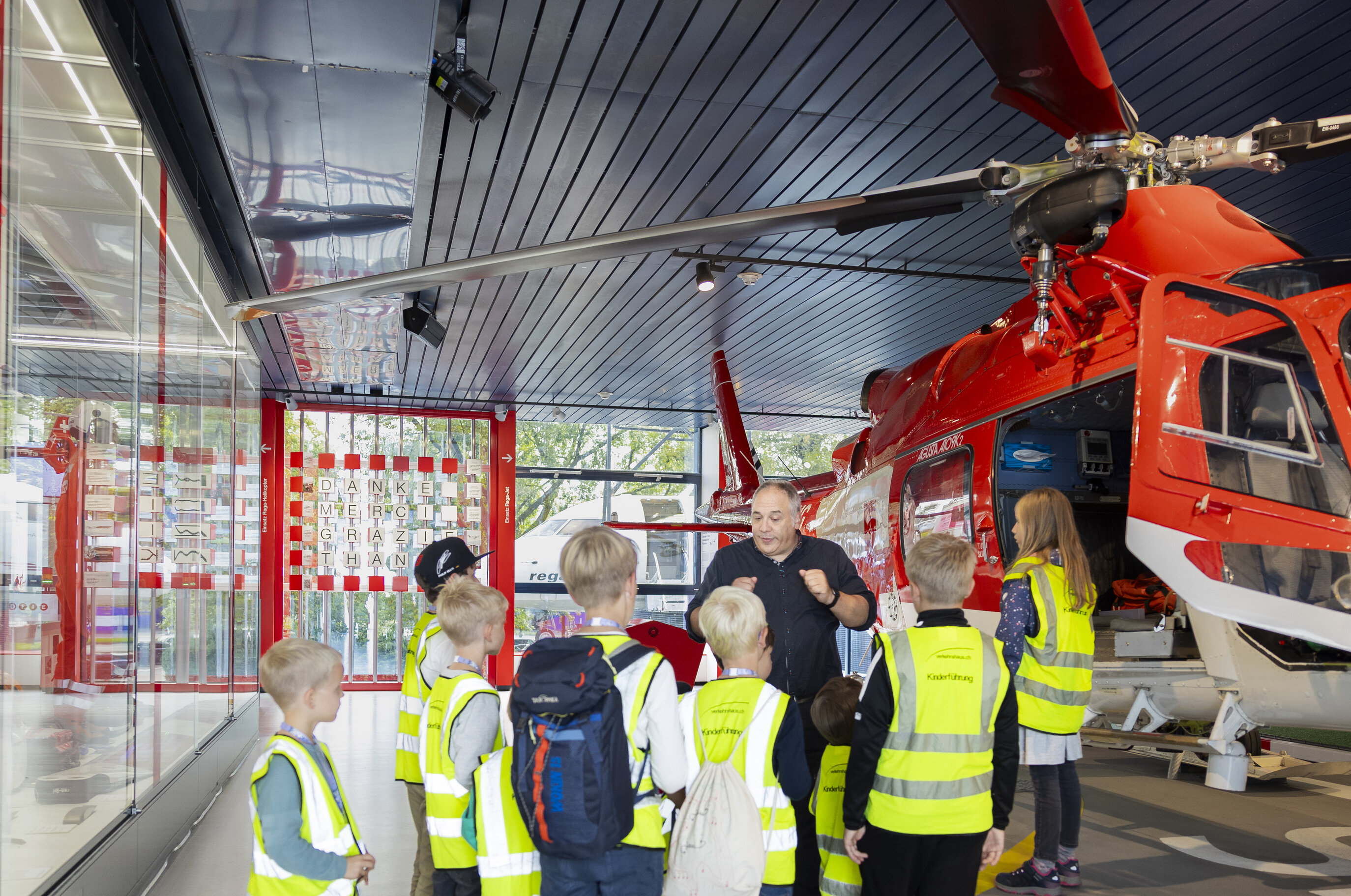 Fünf Kinder mit Leuchtwesten und eine Begleitperson mit Leuchtweste, sie stehen im Verkehrsgarten im Verkehrshaus.