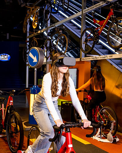 Ein junges Mädchen auf einem stationären Fahrrad trägt ein VR-Headset.
