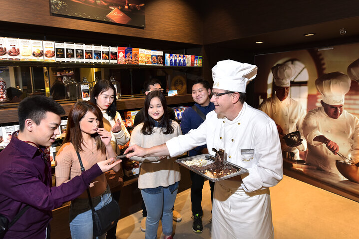 Ein Maitre Chocolatier verteilt Schokolade an Asiaten.