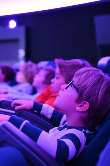 Ein Junge blickt in den Sternenhimmel des Planetariums im Verkehrshaus der Schweiz.