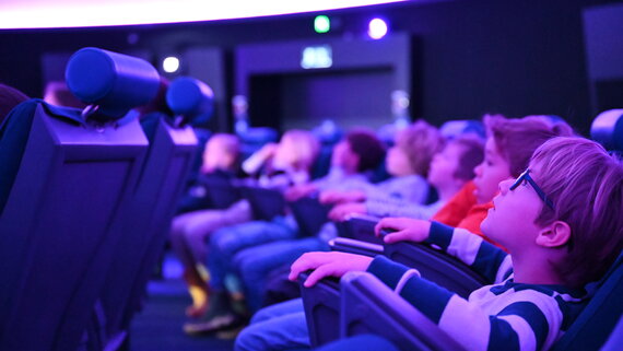 Ein Junge blickt in den Sternenhimmel des Planetariums im Verkehrshaus der Schweiz.
