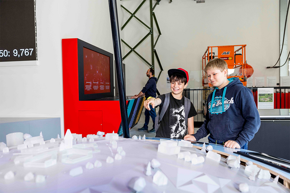 Zwei Kinder erkunden ein 3D-Modell einer Stadt in einer interaktiven Ausstellung.