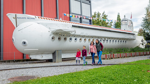 Eine Familie geht an dem U-Boot von Auguste Piccard vorbei, welches im Außenbereich der Schifffahrt und Tourismus Halle steht.