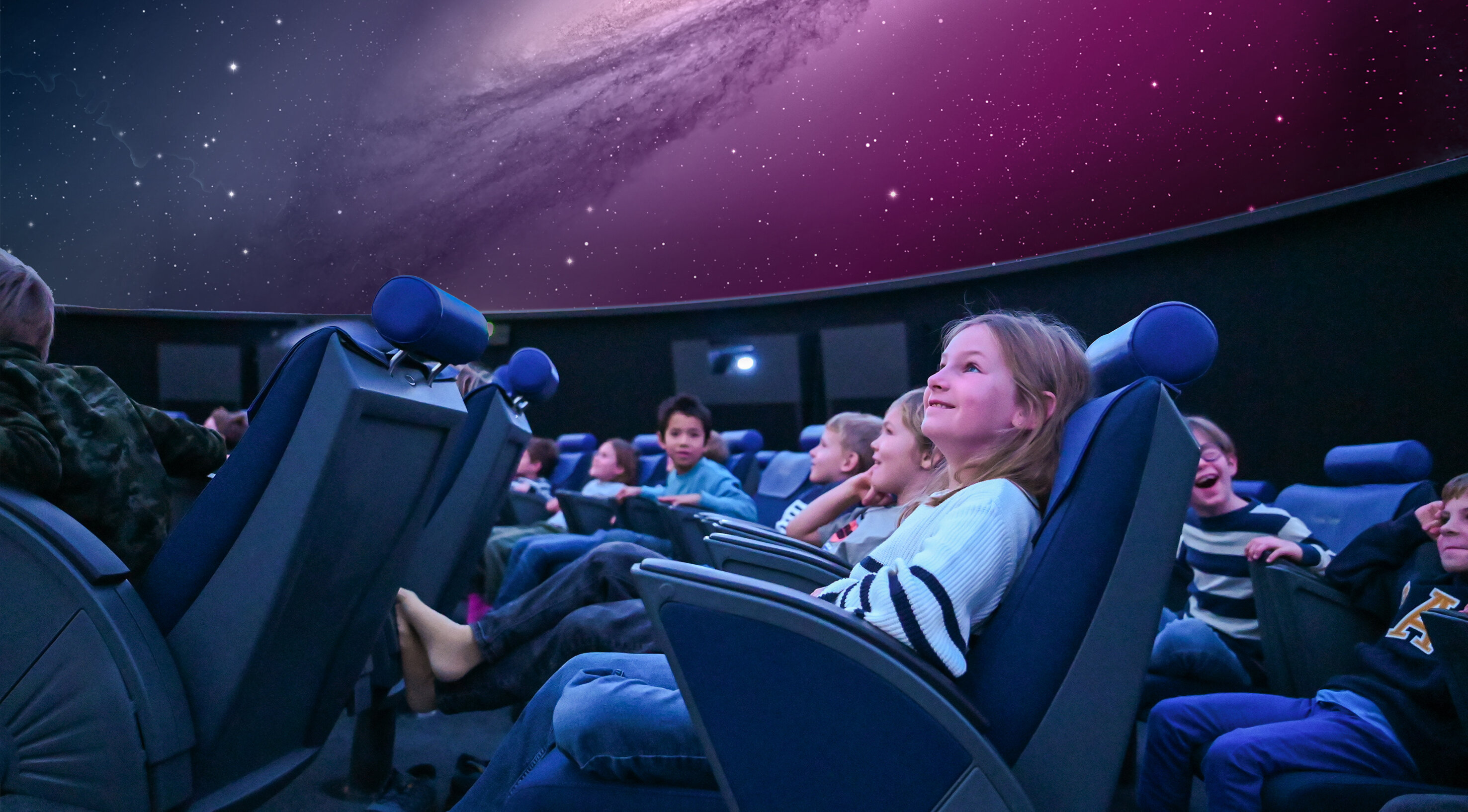 Ein 10 jähriges Mädchen schaut begeistert in den Himmel des Planetariums in Luzern.