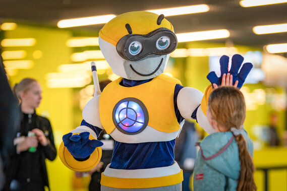 Das Verkehrshaus Maskottchen gibt einem Kind ein high five. 