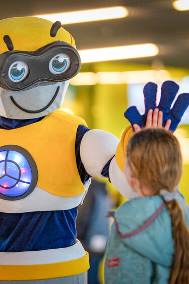 Das Verkehrshaus Maskottchen gibt einem Kind ein high five. 