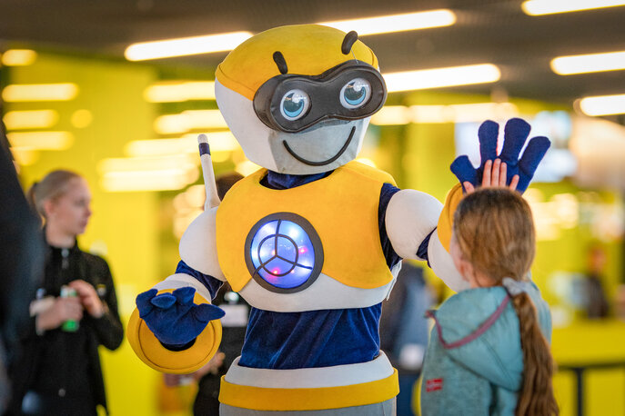 Das Verkehrshaus Maskottchen gibt einem Kind ein high five. 