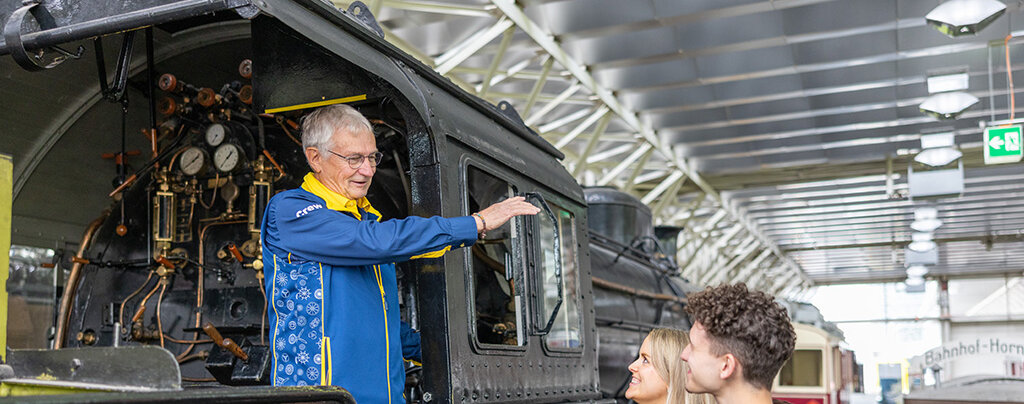 In einer alten Lokomotive erzählt ein Führer Geschichten, während die Besucher gespannt zuhören.