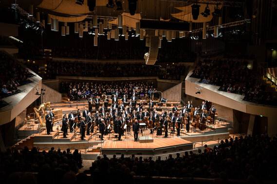 Ein Orchester auf einer Bühne in einem Konzertsaal.