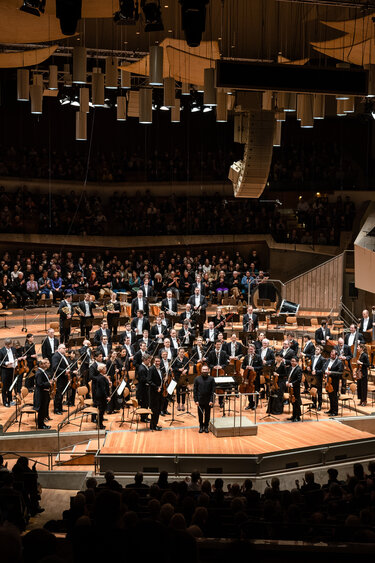 Ein Orchester auf einer Bühne in einem Konzertsaal.