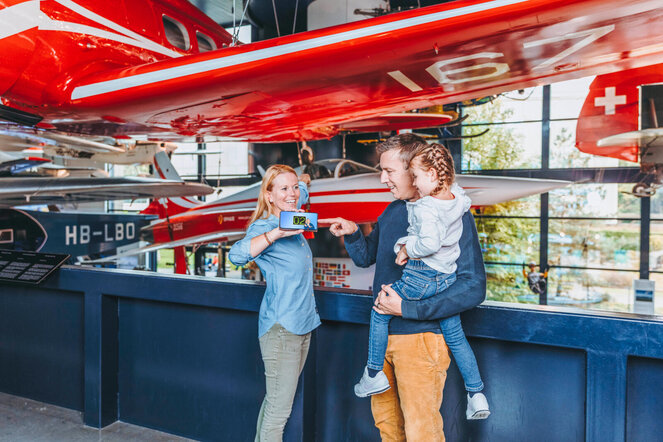 Eine dreiköpfige Familie fotografiert die aufgehängten Flieger in der Halle L&R.
