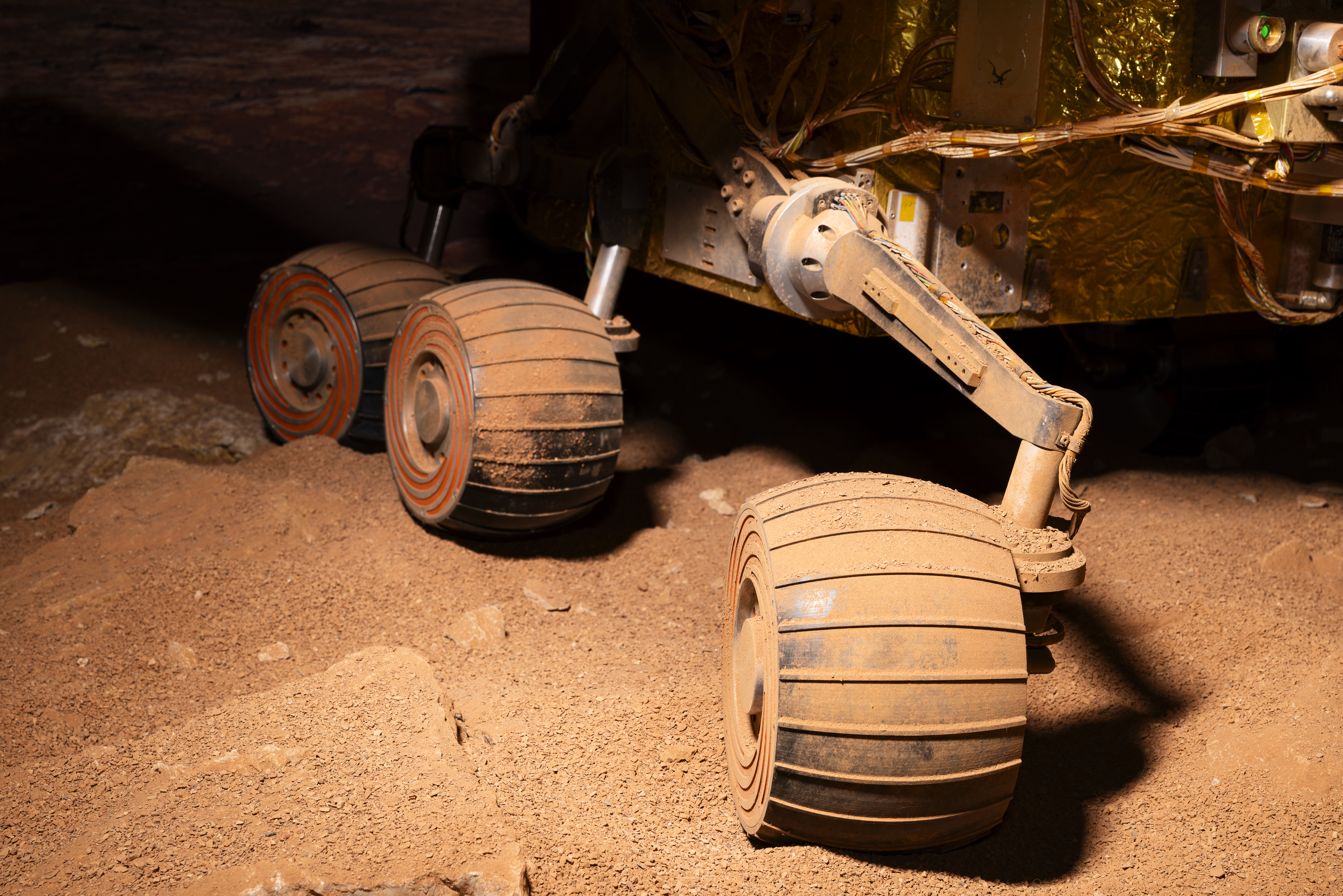 Ein Rad eines Marsrovers in einer nachgestellten Marslandschaft.