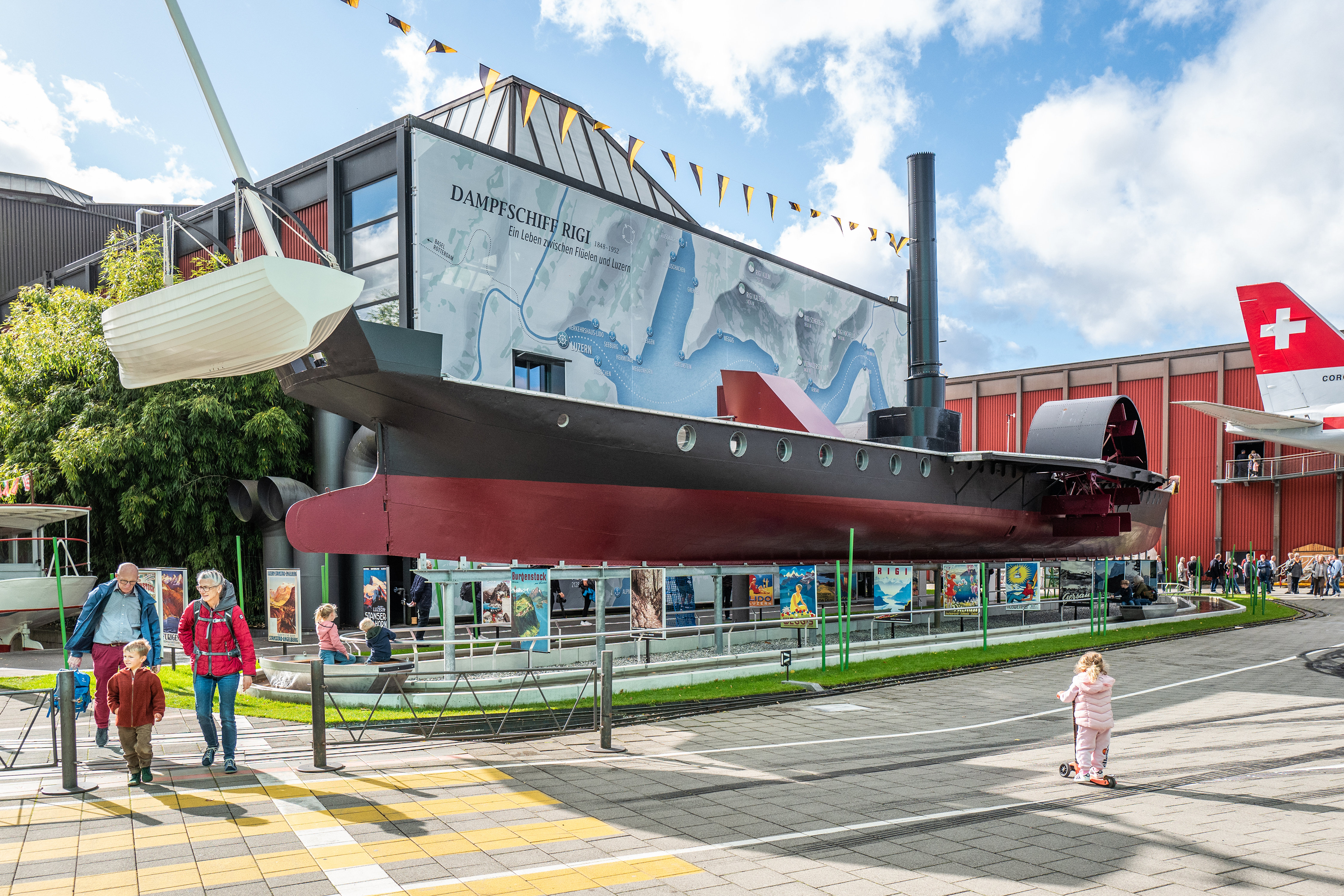 Das Dampfschiff Rigi vor der Halle Schifffahrt mit einer Familie, die das Verkehrshaus besucht.