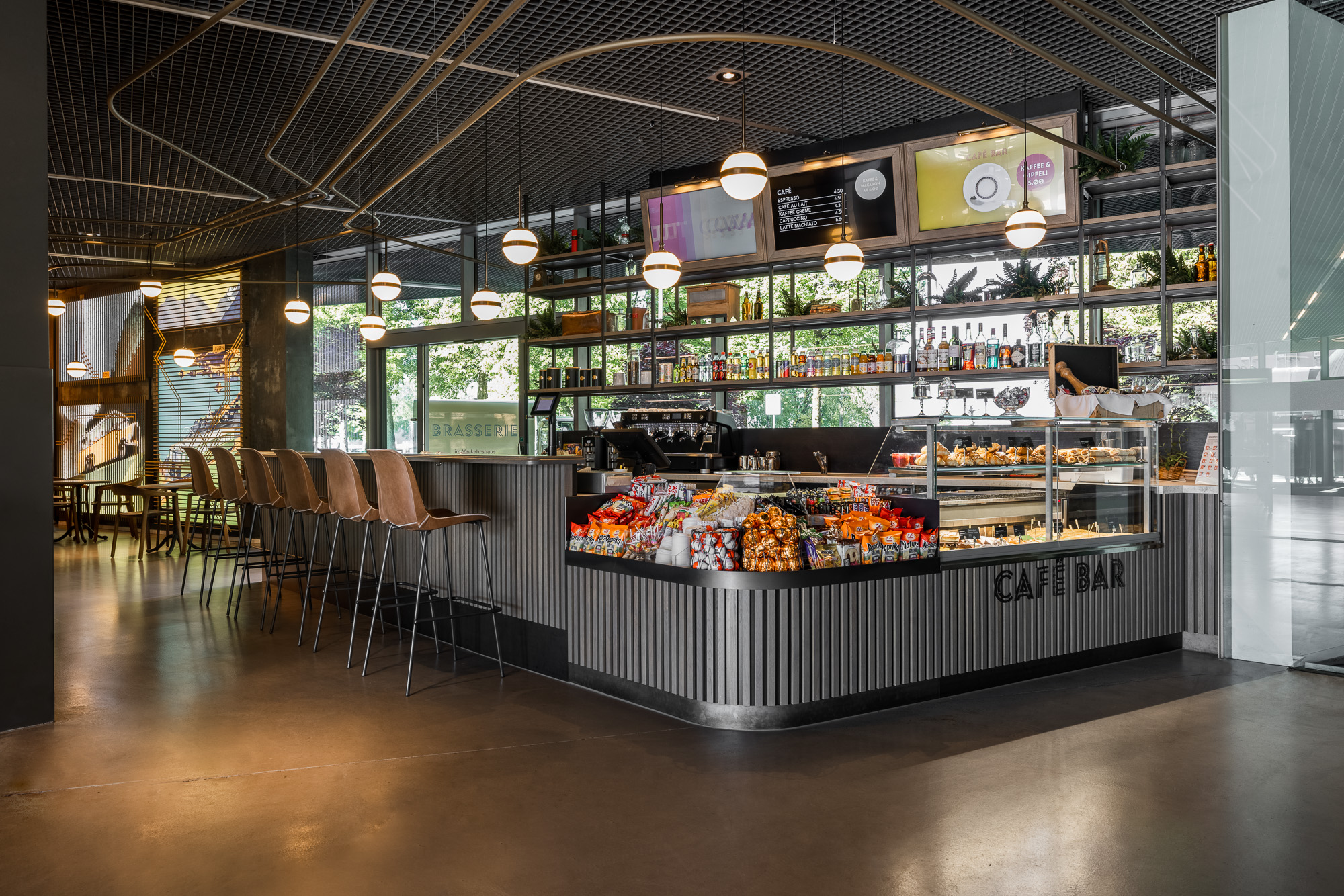 Eine Café Bar mit Theke und Barhockern und Snacks.