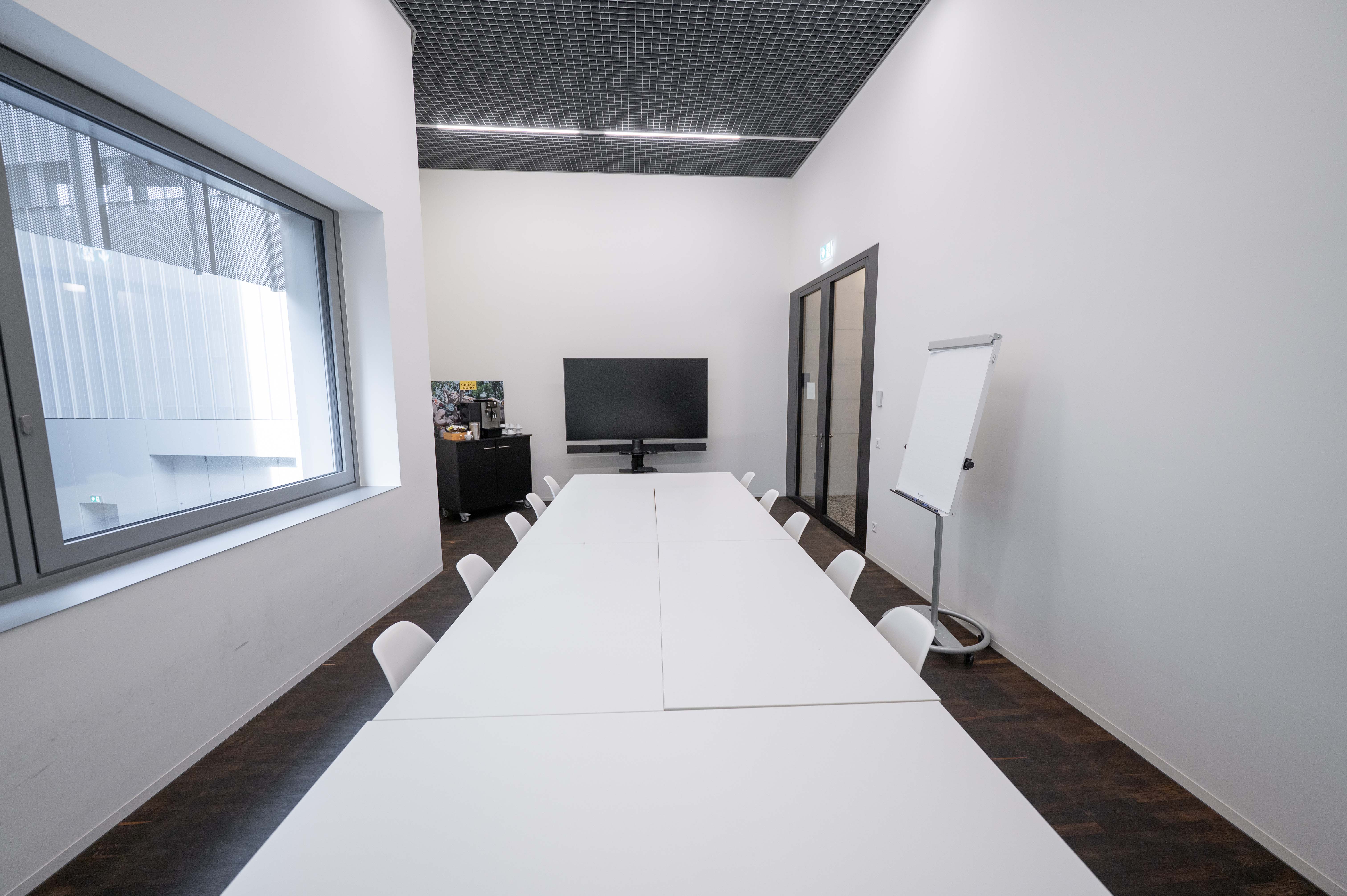 Ein Sitzungsraum mit Betonwänden und einem Tisch mit Stühlen rundherum.
